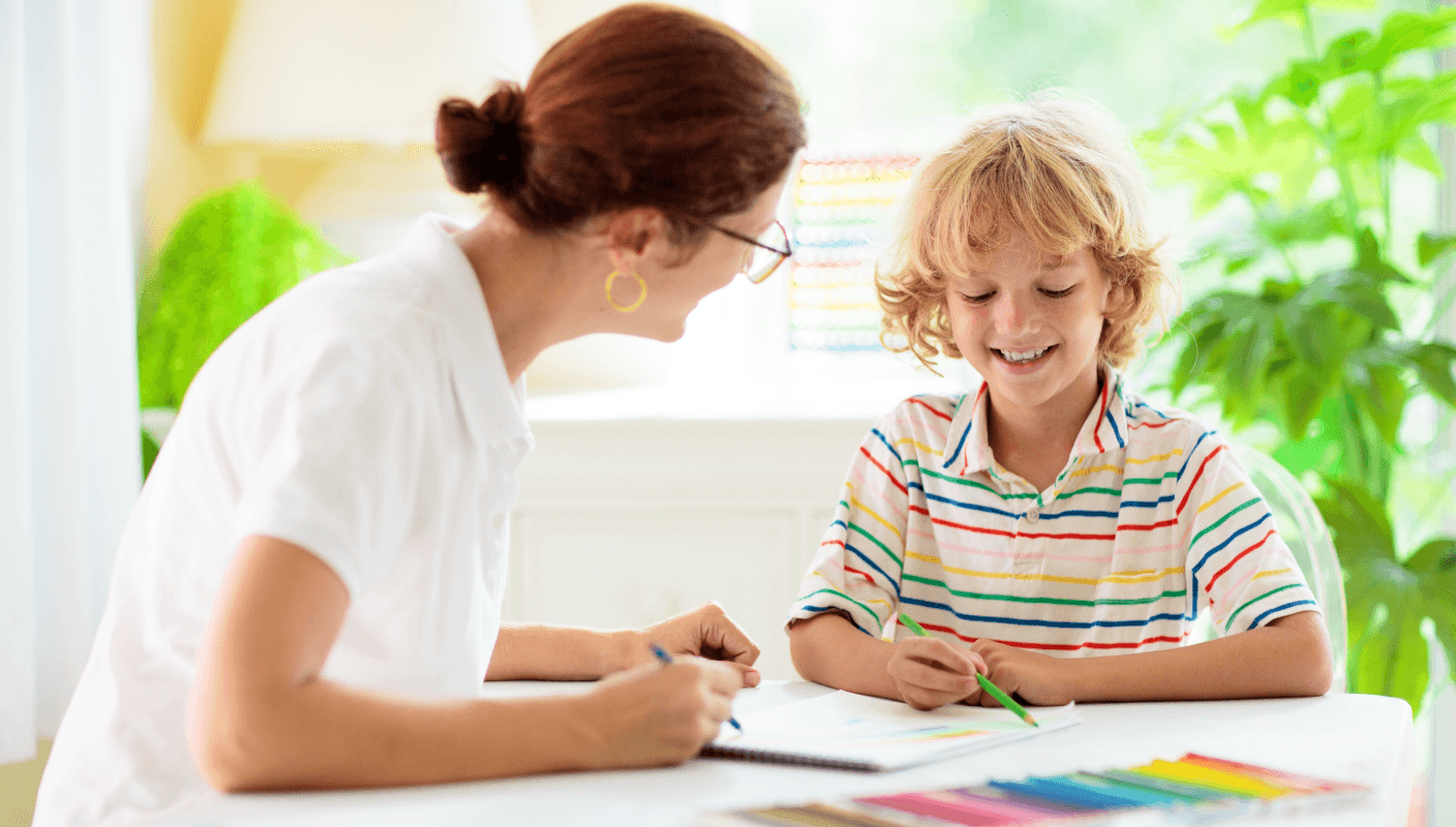 A lady helping a child work on a laptop