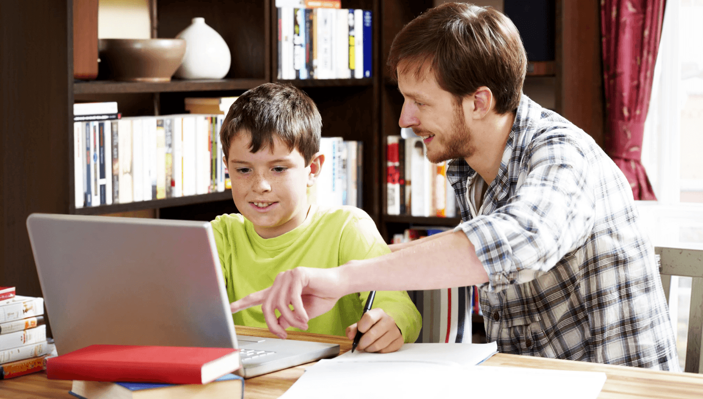 A lady helping a child work on a laptop