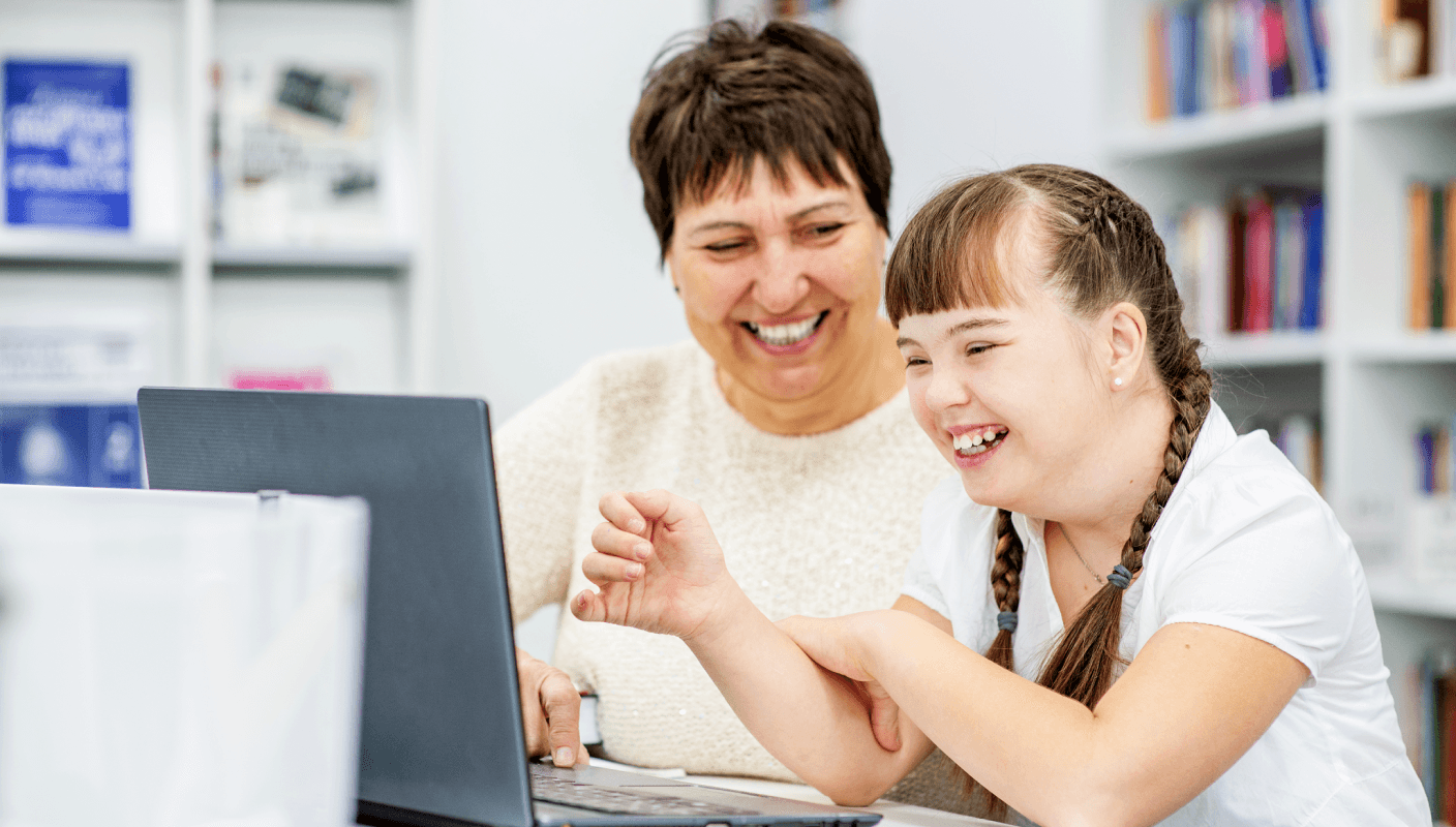 A lady helping a child work on a laptop