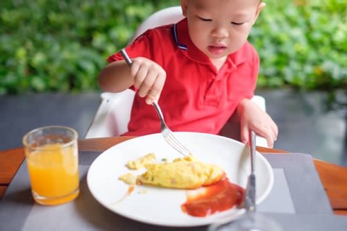 child struggling to use knife and fork