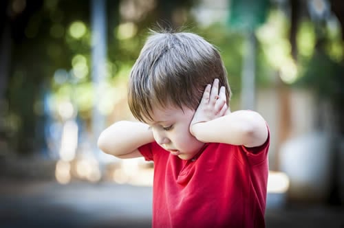 child covering their ears from loud noises