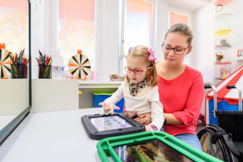 Non-verbal girl, learning to use digital tablet as speech-generating device.