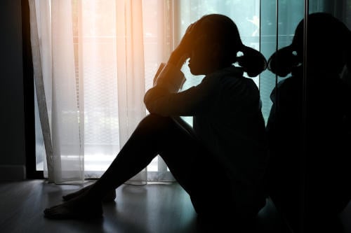 girl sitting alone in her room feeling overwhelmed