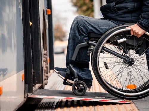 Person with a physical disability enters public transport with an accessible ramp.