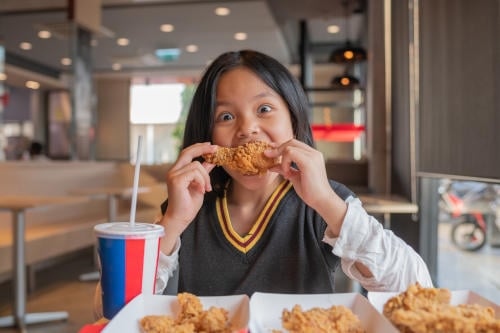 child loving eating chicken