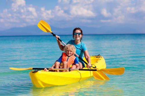 child kayaking with mother at the beach