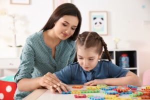 Young woman and little girl with autistic disorder playing at home