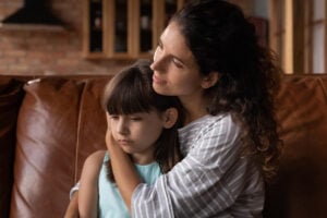 Caring mother cuddles unhappy autistic girl