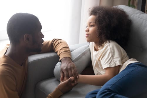 Father hold hand anxious daughter lying on sofa 