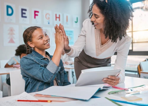 teacher and dyslexic child high fiving after achieving progress in the classroom
