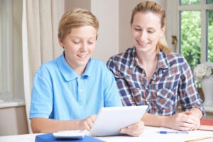 Female Home Tutor Helping Boy With Studies Using Digital Tablet