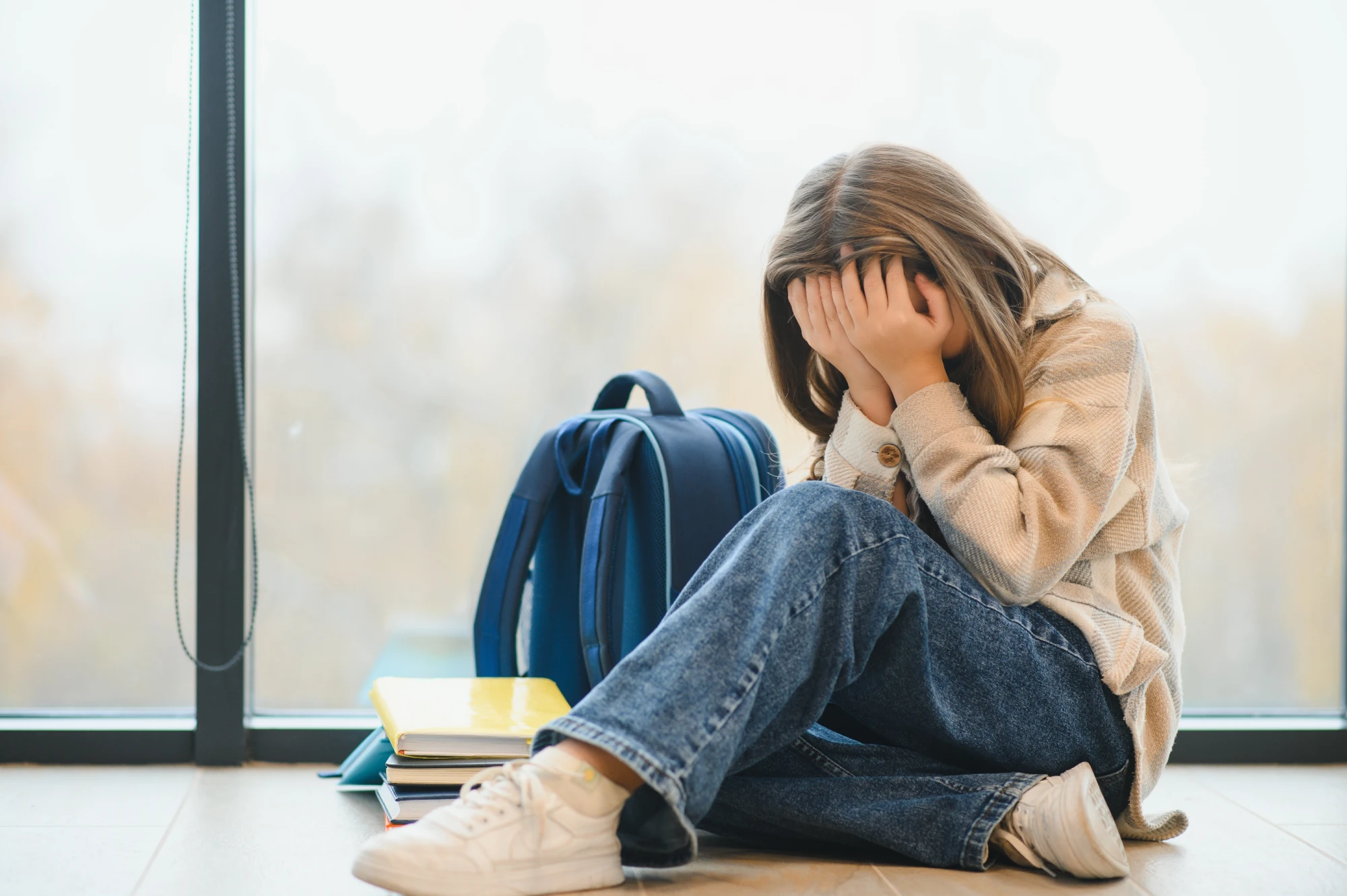 child sitting in shool corridor upset