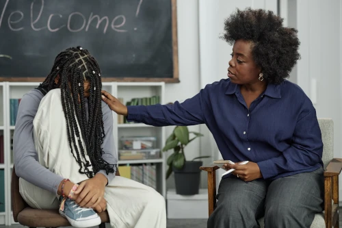 girl suffering from school trauma, being comforted by a teacher