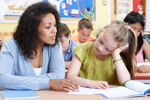 dyslexic child getting help by the teacher in class