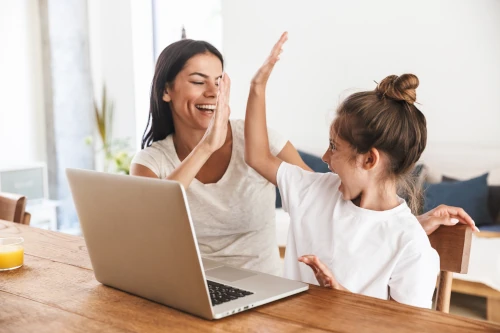 PArent and PDA child working together and high fiving on a computer